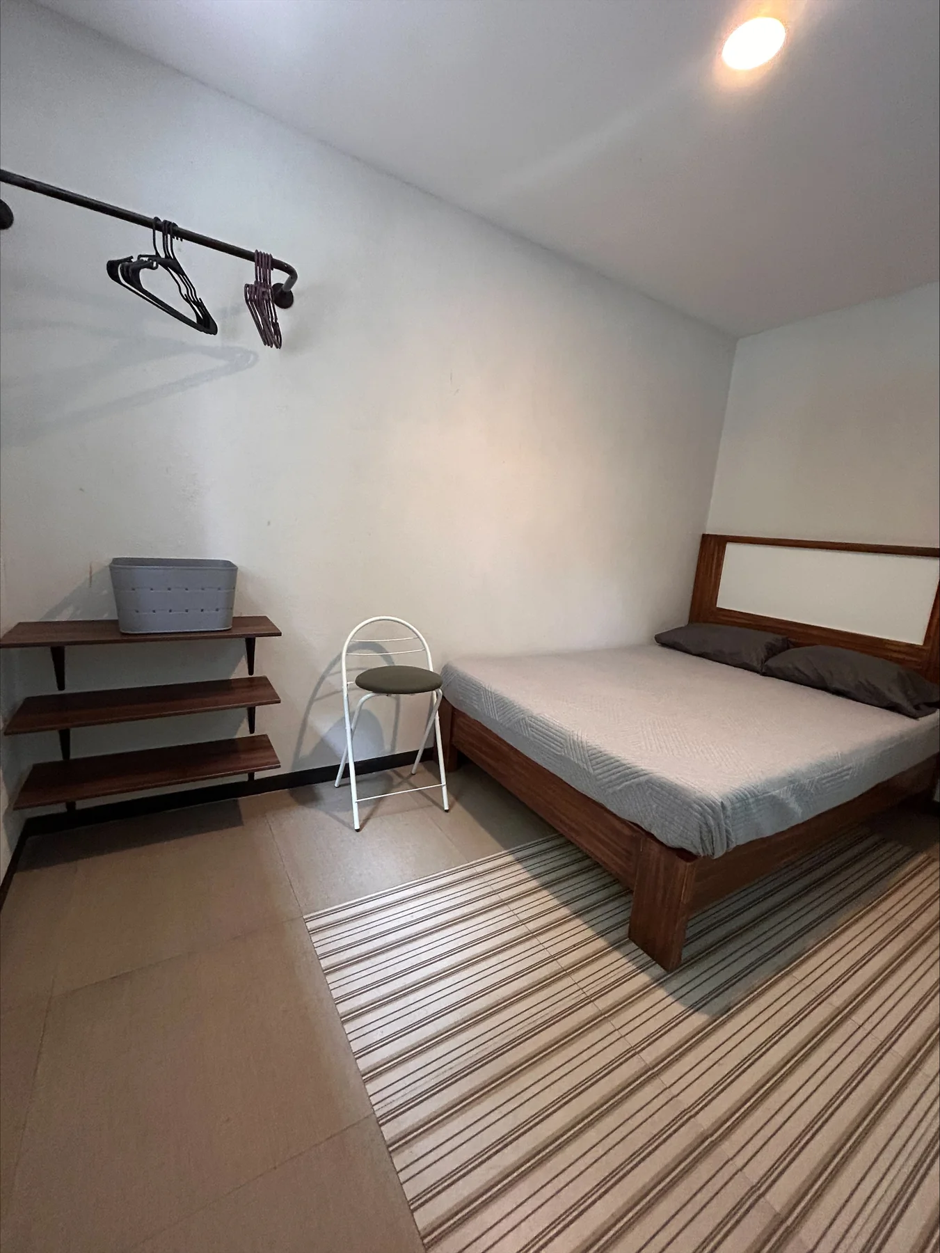 Habitación amplia con cama, silla y estantes